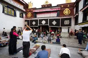 Local Tibetan pilgrims prostrating and praying in front of Jokhang Temple in Lhasa, the spiritual heart of Tibet and a sacred pilgrimage site for Buddhists.