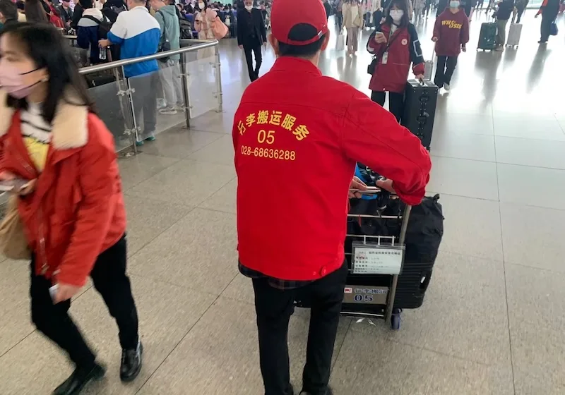 A Red Cap porter assisting a traveler with luggage at Chengdu East railway station